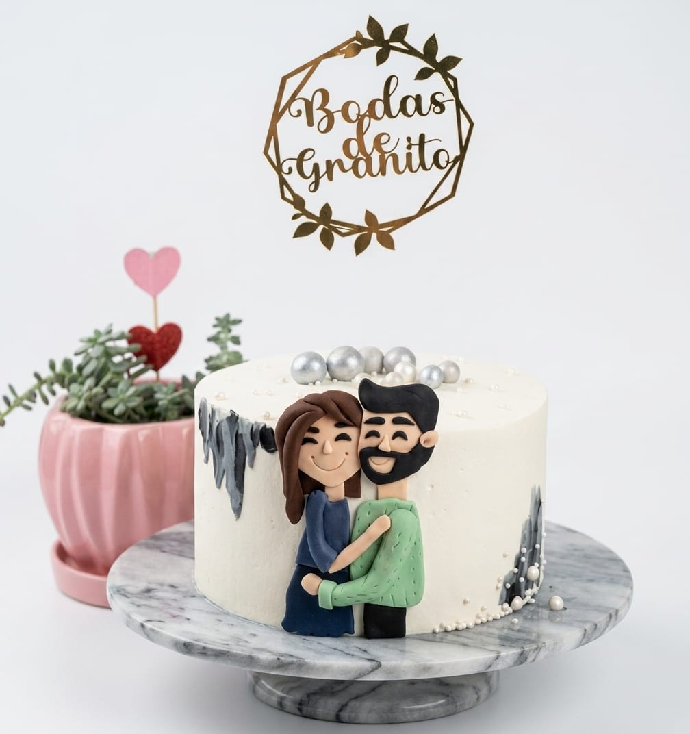 Torta de aniversario con figuras de una pareja modeladas a mano y topper de bodas de granito