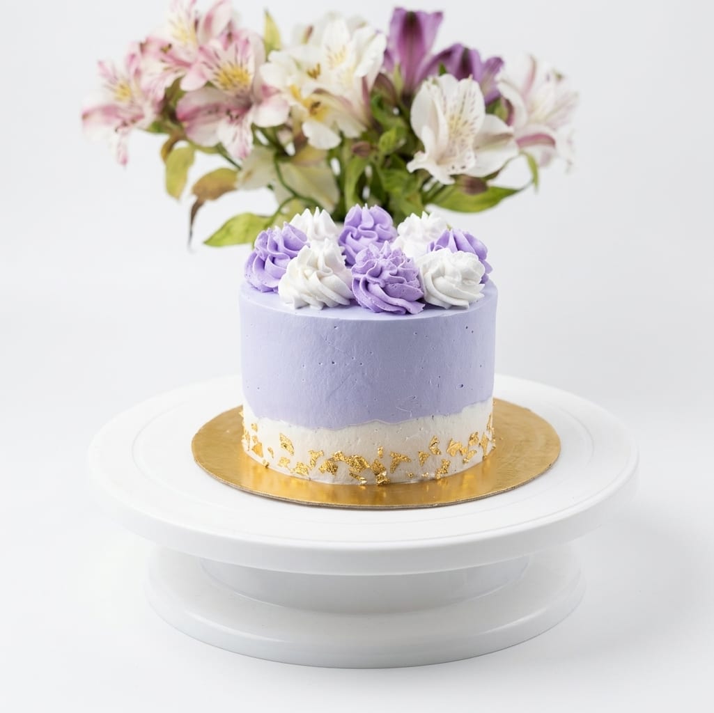 Torta lila con rosetones morados y blancos y detalle de pan de oro